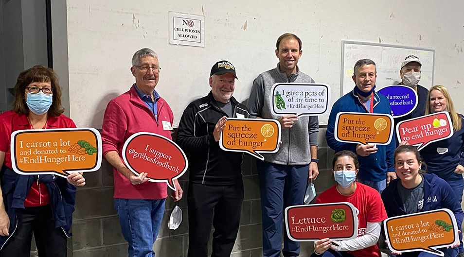Volunteers posing at food bank with signs featuring food-related puns